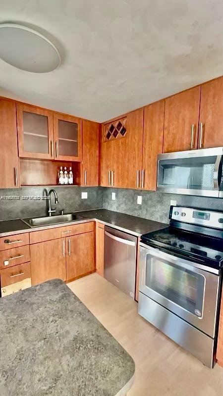 A kitchen features wood cabinets, stainless steel appliances, a gray countertop, and a gray backsplash — 1631 NE 114th St # 201, Miami FL 33181, MIAMI, FL