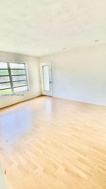 An empty room features light wood-look flooring, white walls, and a large window — 1631 NE 114th St # 201, Miami FL 33181, MIAMI, FL
