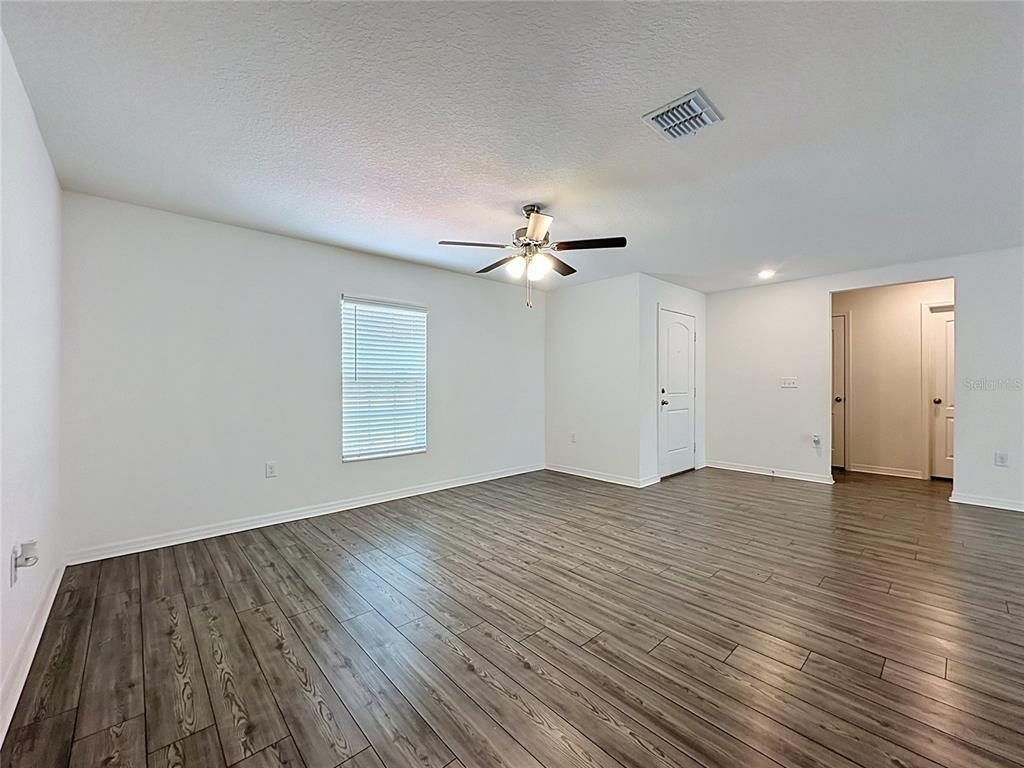 An empty room with white walls, wood-look flooring, a ceiling fan, and a window — 1407 HILLSBOROUGH WAY, POINCIANA, FL
