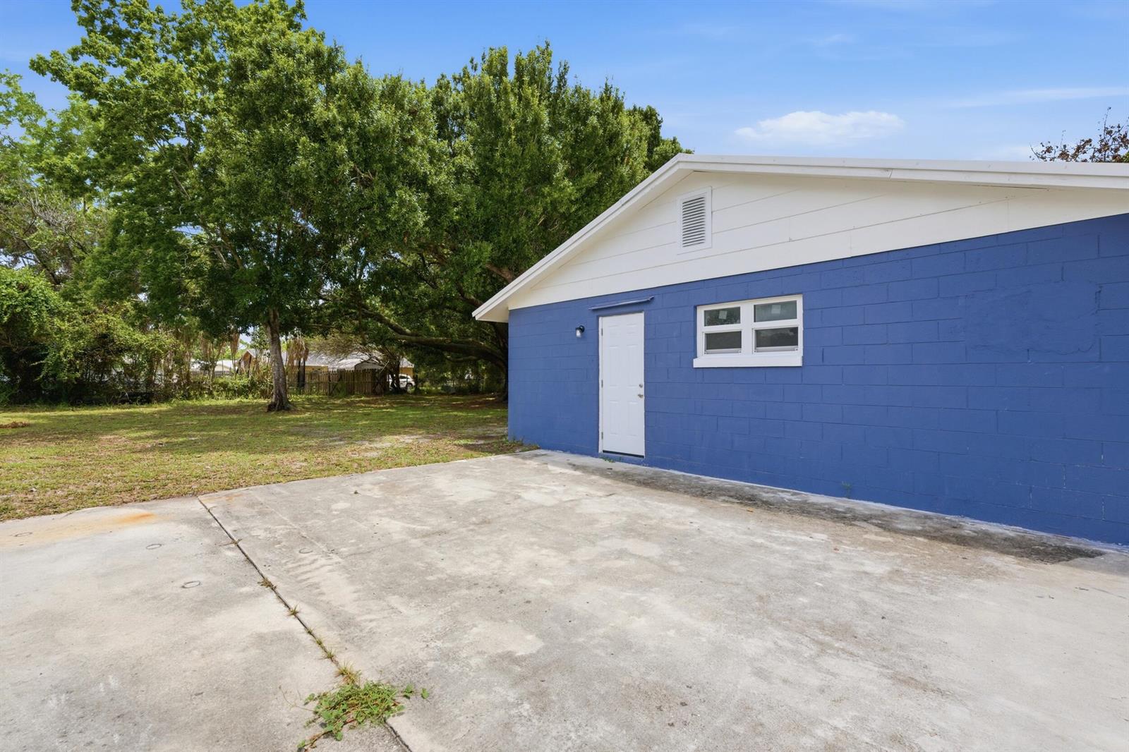 A blue concrete block building with a white door and window sits beside a driveway — 3000 Langston Drive, Fort Pierce FL 34946, FORT PIERCE, FL