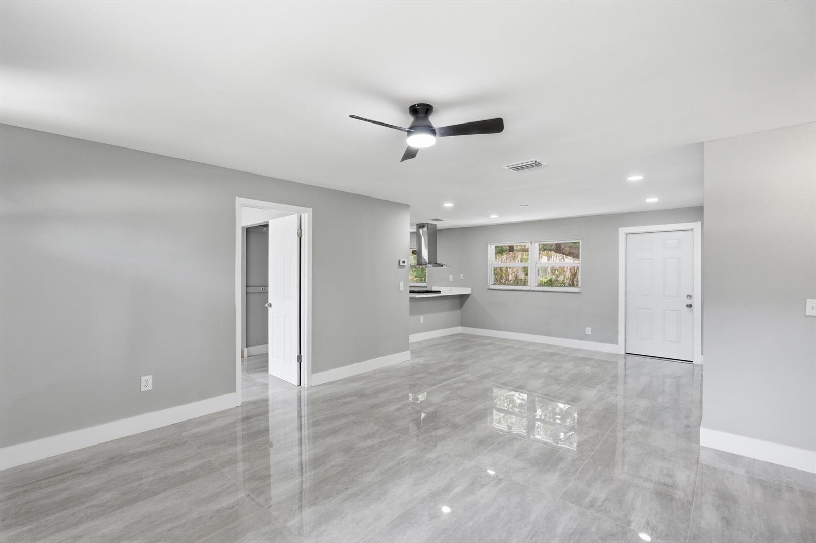 A bright, open-concept room features gray walls, glossy tile flooring, and a ceiling fan — 3000 Langston Drive, Fort Pierce FL 34946, FORT PIERCE, FL
