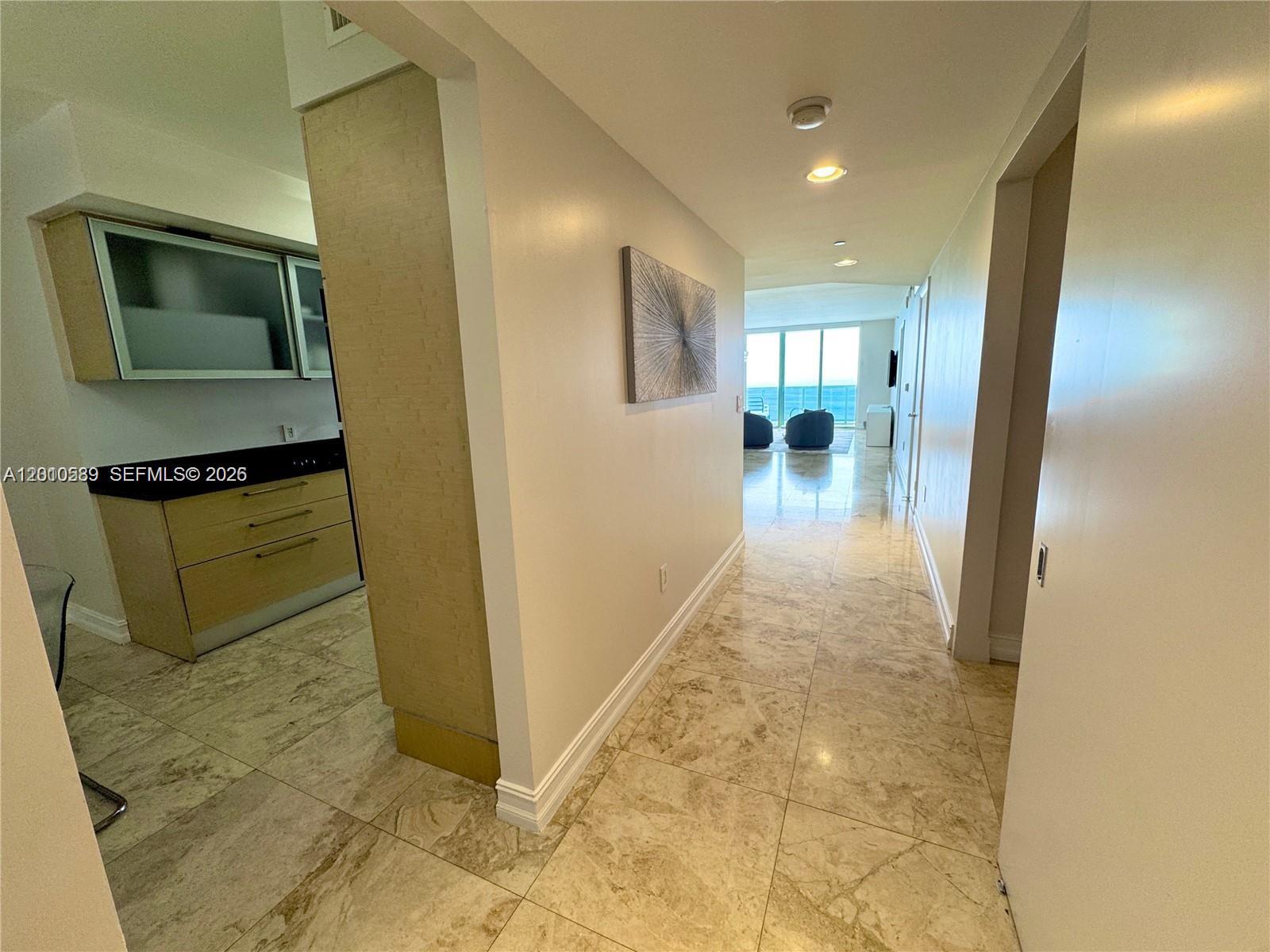 A hallway with marble floors leads to a living area with floor-to-ceiling windows — 1800 S Ocean Dr # 2602, Hallandale Beach FL 33009, HALLANDALE BEACH, FL