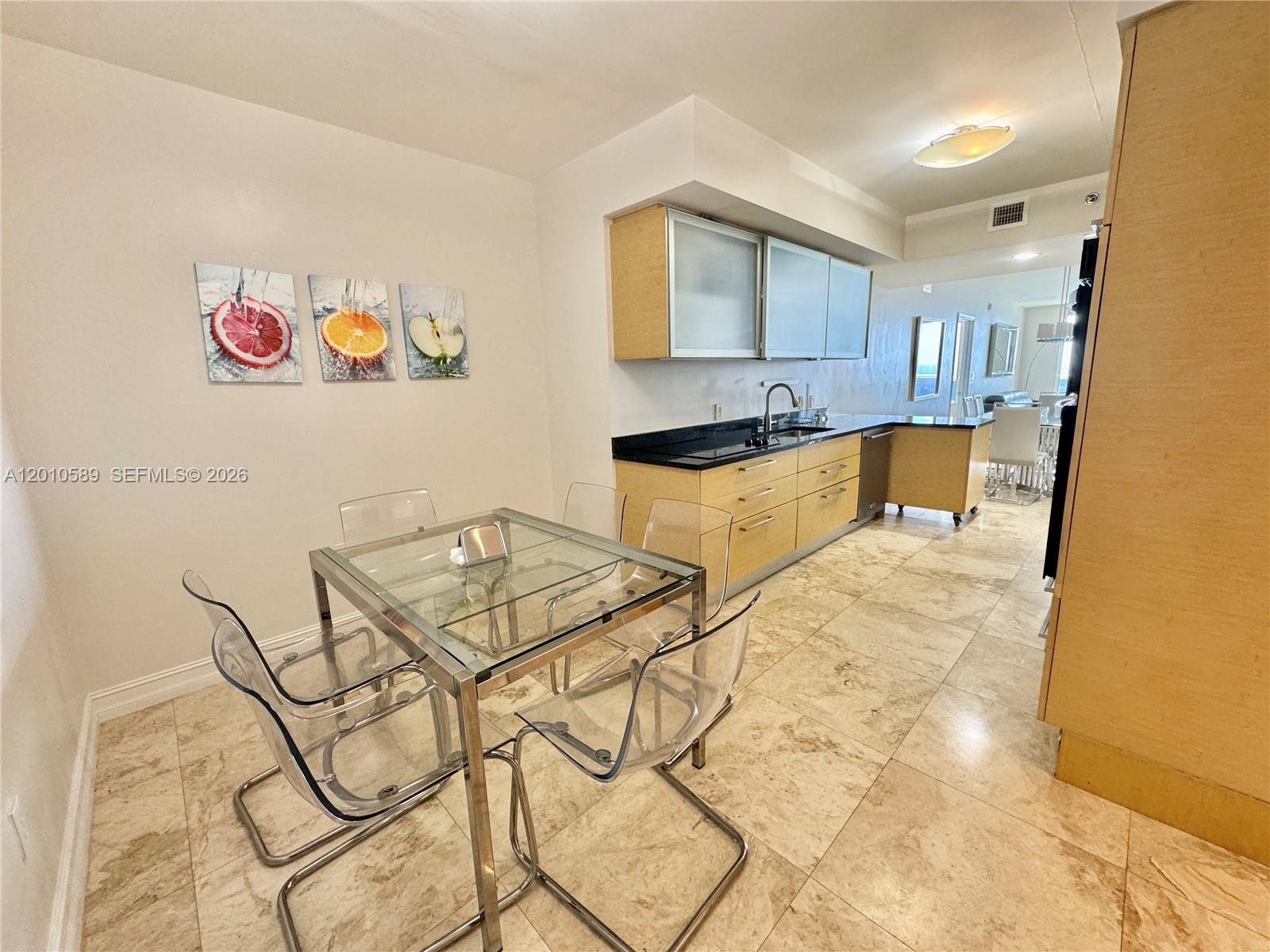 A kitchen with light wood cabinets and a glass dining table sits on tile floors — 1800 S Ocean Dr # 2602, Hallandale Beach FL 33009, HALLANDALE BEACH, FL