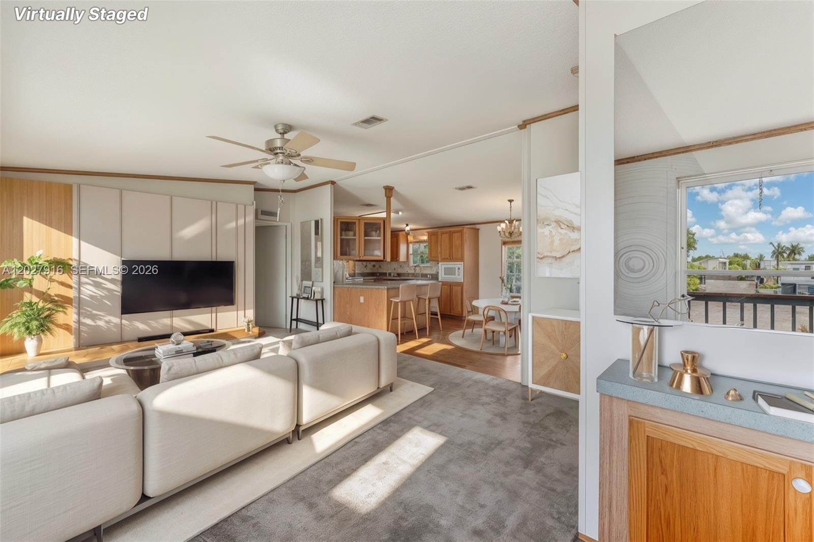 A living room with a sectional sofa, television, and an adjacent kitchen with wooden cabinets — 19800 SW 180 avenue #524, Miami FL 33187, MIAMI, FL