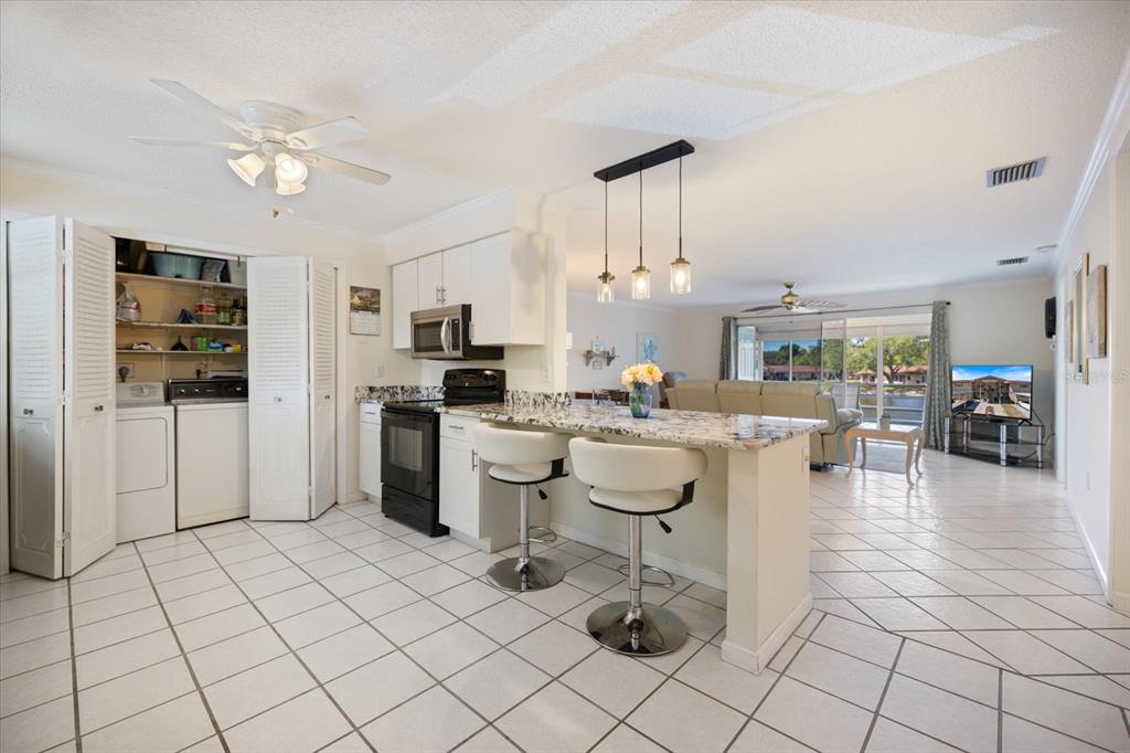 An open-concept kitchen and dining area with tile flooring, a breakfast bar, and pendant lighting — 4522 NARRAGANSET TRAIL UNIT 84, SARASOTA, FL