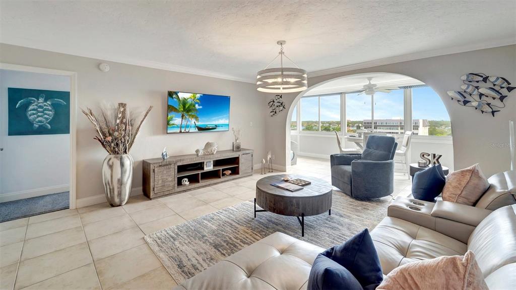 A living room features tile floors, a television, a round coffee table, and a sunroom — 1125 W PEPPERTREE DRIVE UNIT 705, SARASOTA, FL