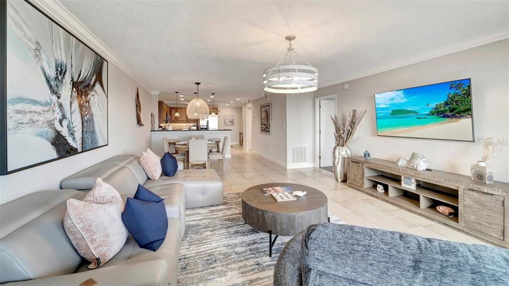 A living room with a grey sectional, round coffee table, and a wall-mounted television — 1125 W PEPPERTREE DRIVE UNIT 705, SARASOTA, FL