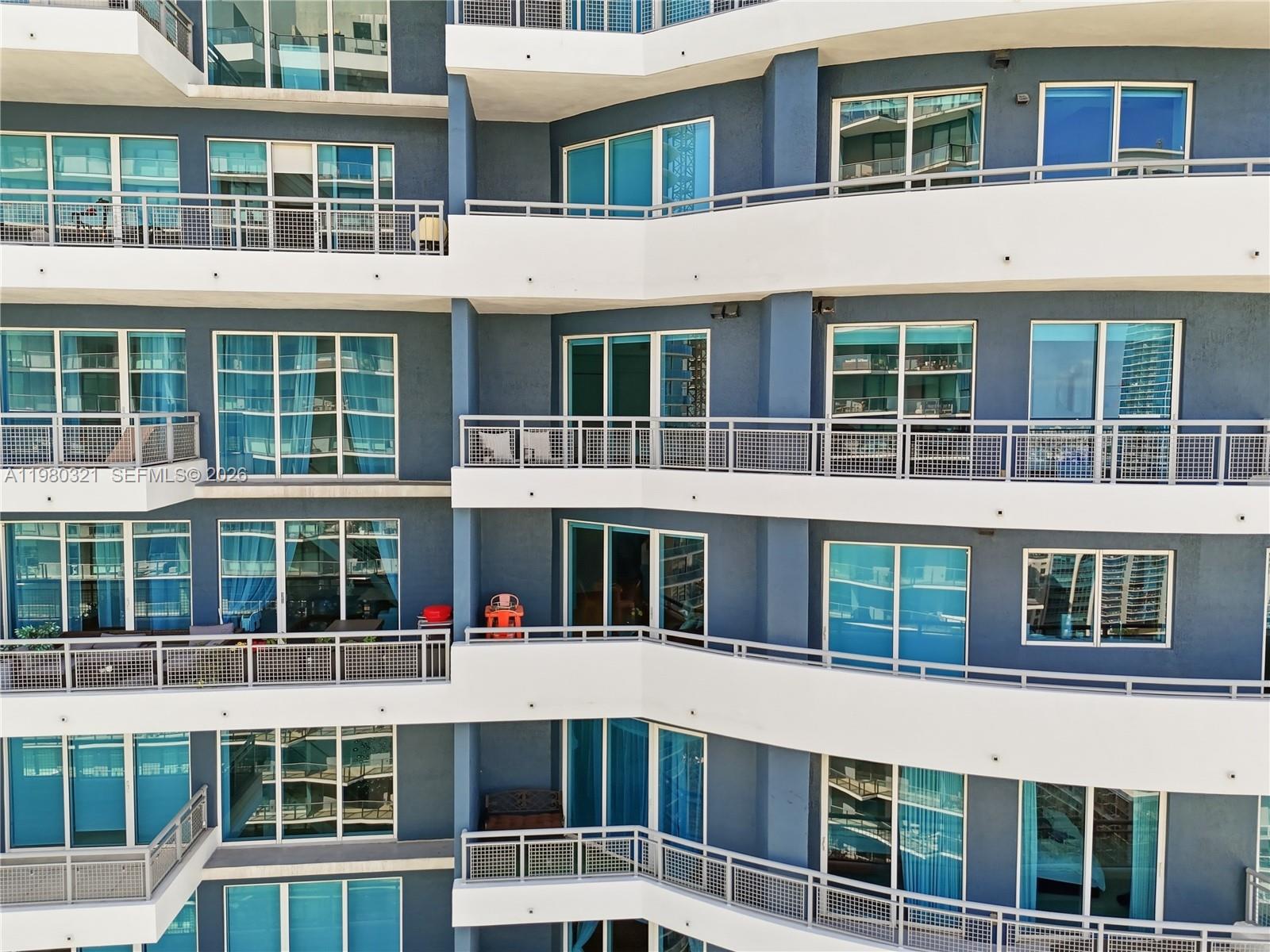 The exterior of a multi-story apartment building features blue walls and white balconies — 60 SW 13th St # 4414, Miami FL 33130, MIAMI, FL