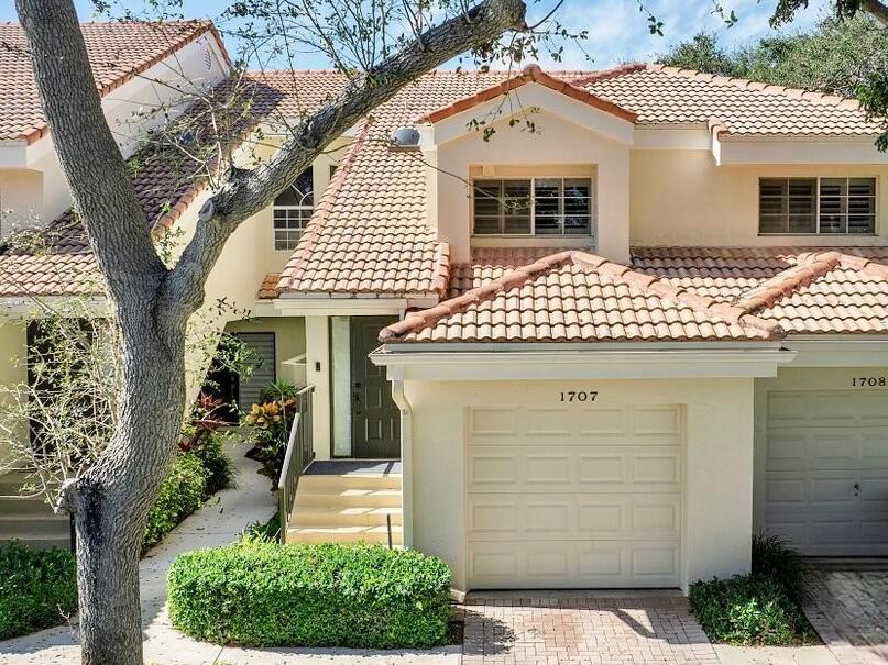 A two-story townhouse features a beige stucco exterior, a tiled roof, and a garage — 17270 Boca Club Boulevard # 1707, Boca Raton FL 33487, BOCA RATON, FL