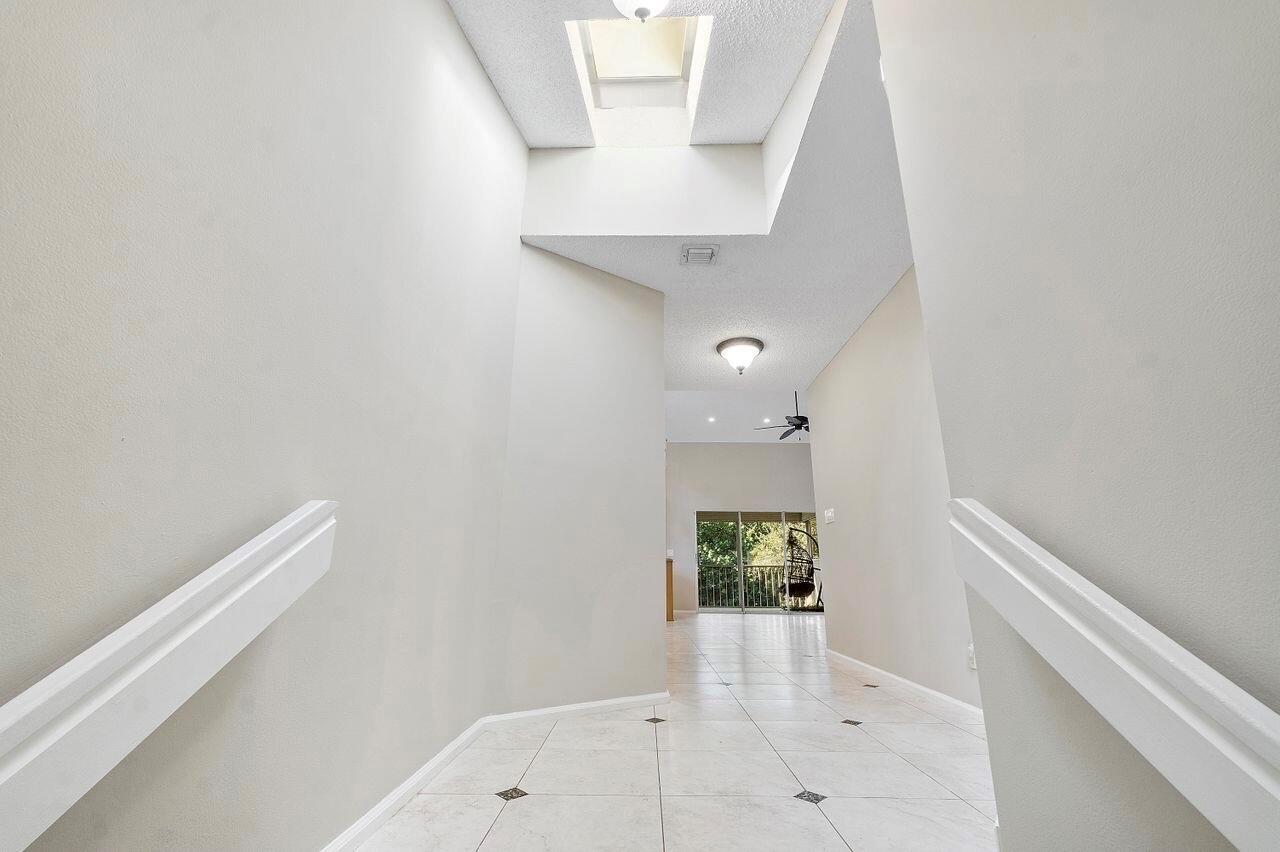 A bright entryway features white tile flooring, a high vaulted ceiling, and a staircase railing — 17270 Boca Club Boulevard # 1707, Boca Raton FL 33487, BOCA RATON, FL