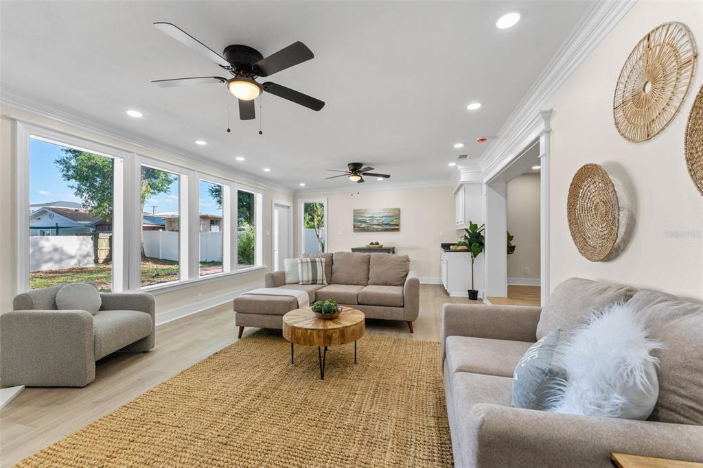 A bright living room features a sectional sofa, a round wooden table, and large windows — 1714 W SAINT ISABEL STREET, TAMPA, FL