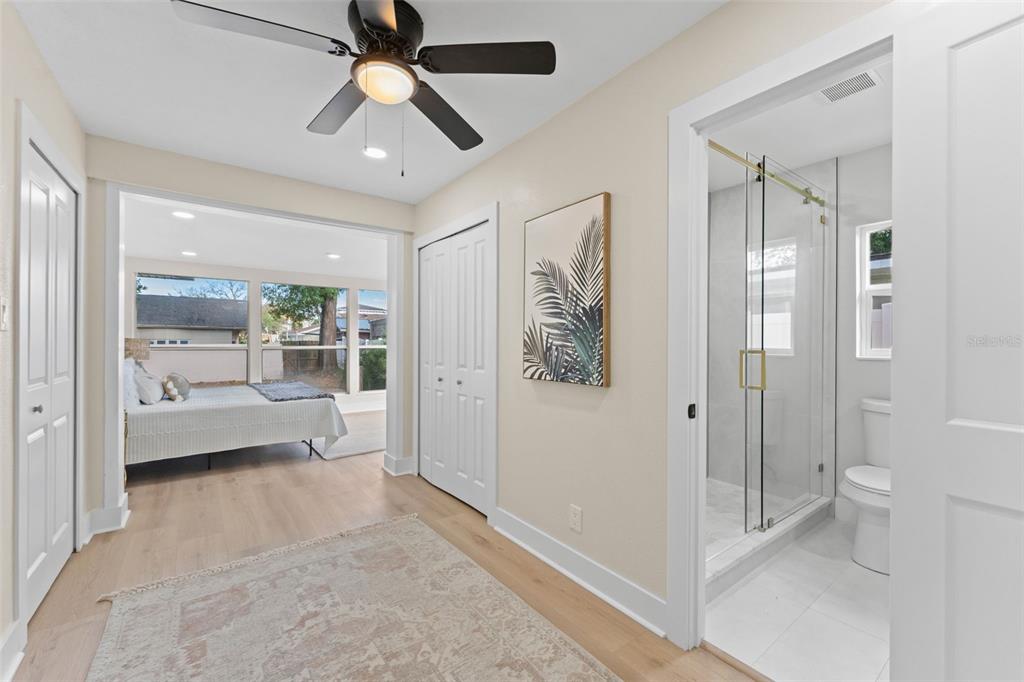 A hallway with light wood floors leads to a bedroom and a bathroom with glass shower — 1714 W SAINT ISABEL STREET, TAMPA, FL