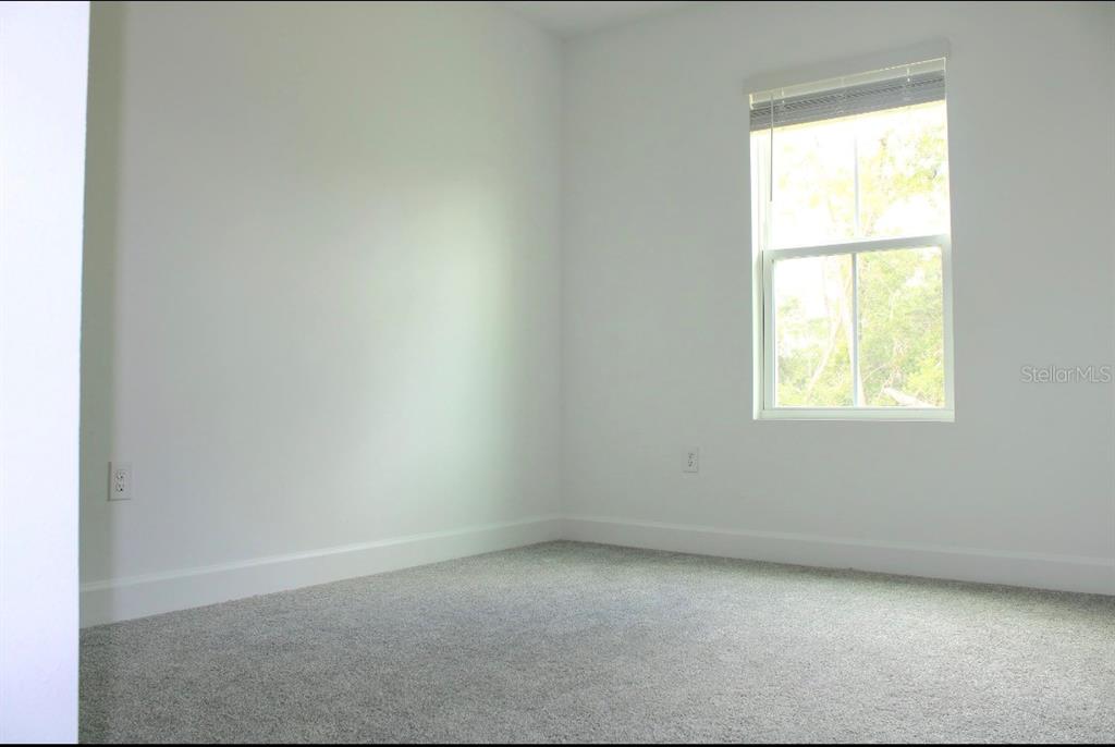 An empty bedroom features white walls, gray carpet, and a single window with blinds — 5186 SW 165TH ST RD, OCALA, FL