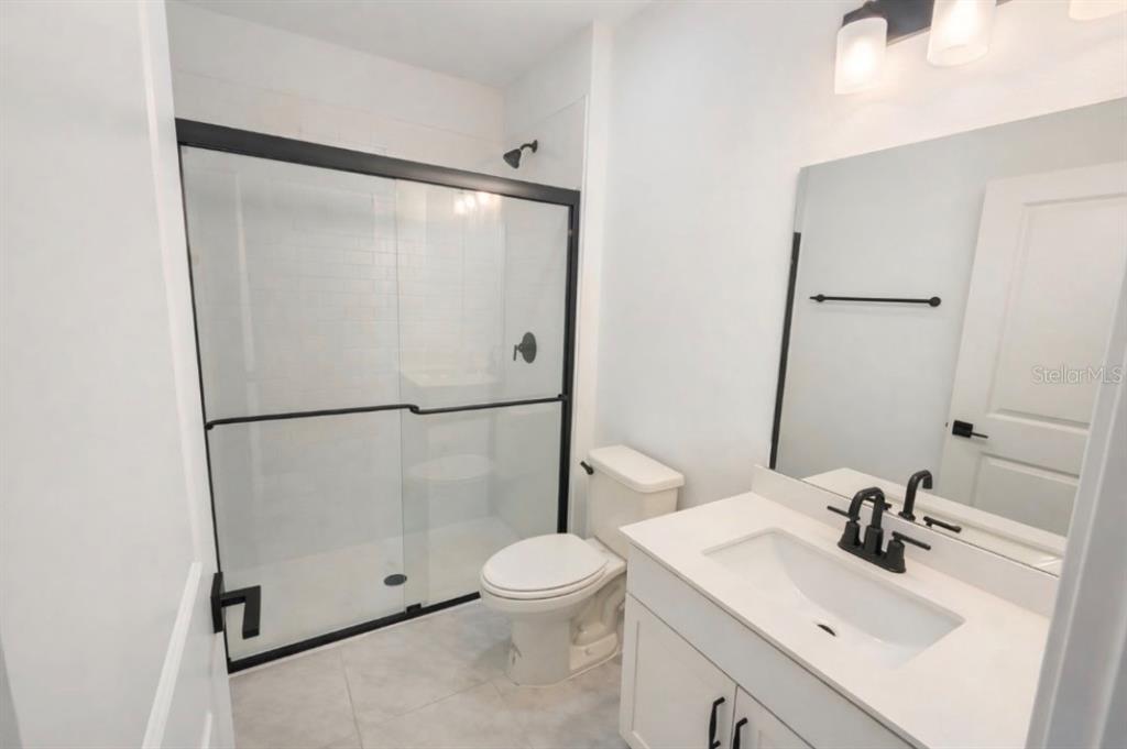 A modern bathroom features a white vanity, a toilet, and a glass-enclosed walk-in shower — 5186 SW 165TH ST RD, OCALA, FL