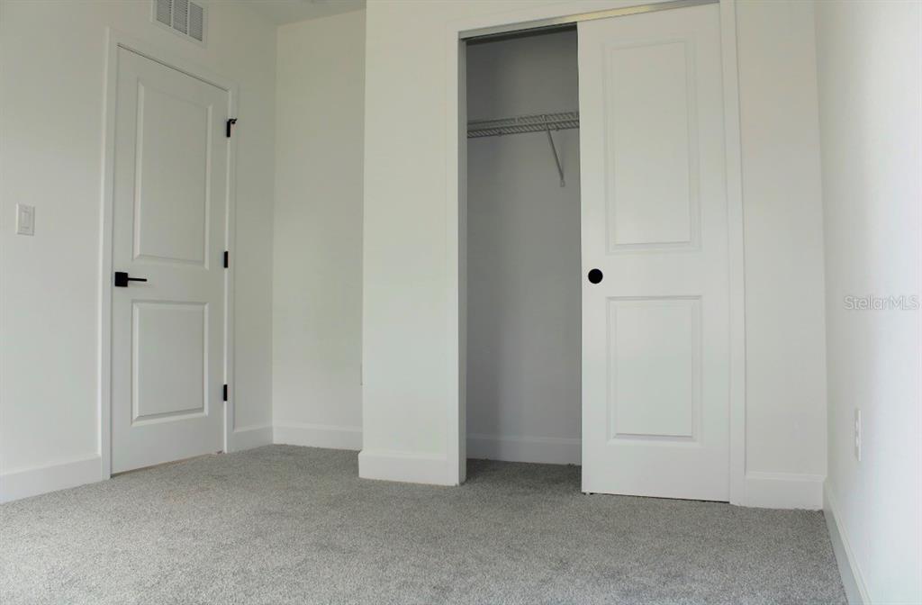 A bedroom with white walls, gray carpet, a closet, and a closed door — 5186 SW 165TH ST RD, OCALA, FL
