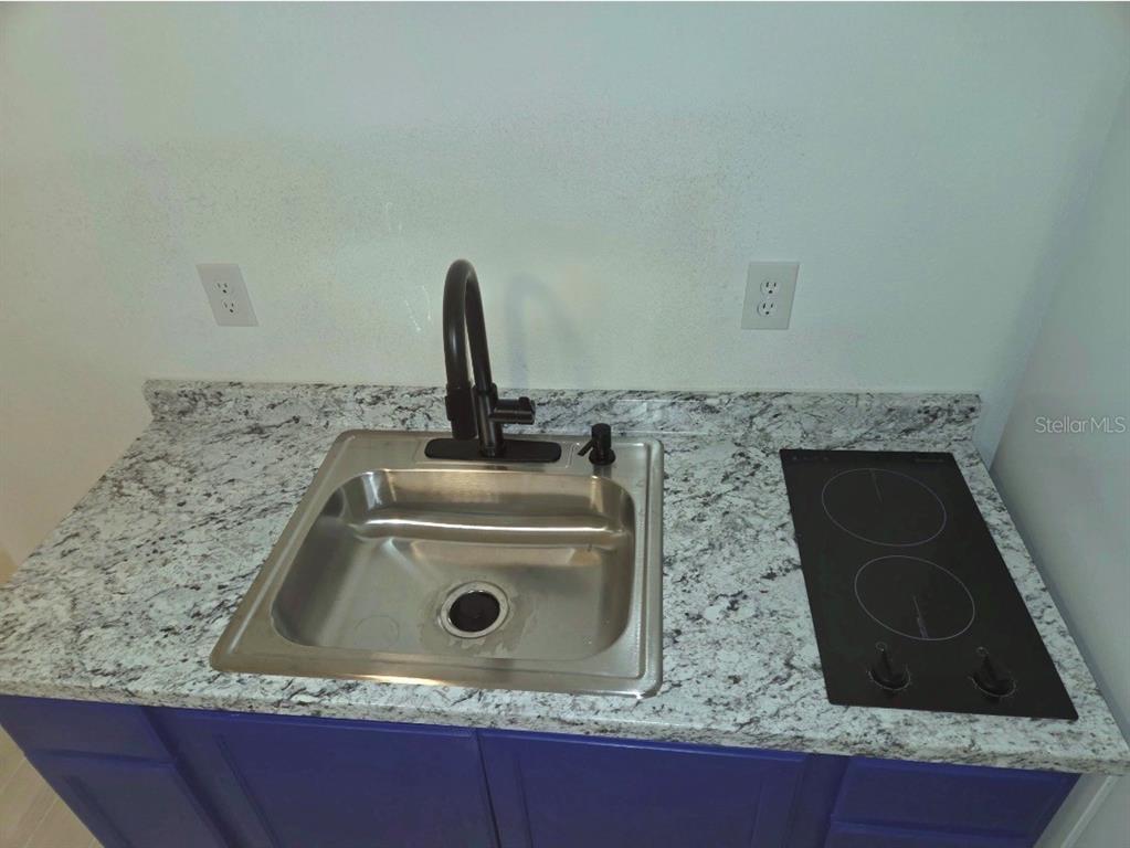 A kitchenette features a stainless steel sink, black faucet, and cooktop on granite countertops — 5186 SW 165TH ST RD, OCALA, FL