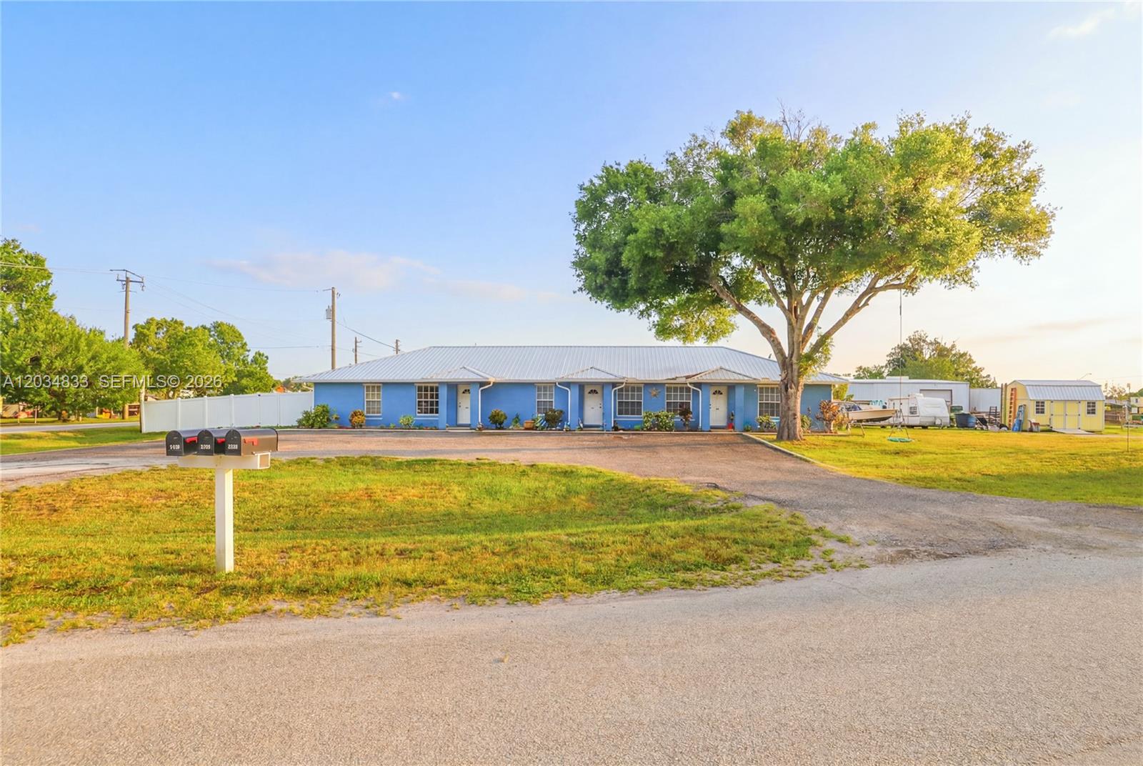 A blue, single-story multi-unit building with a metal roof sits on a large grassy lot — 810 SW 2nd St, Okeechobee FL 34974, OKEECHOBEE, FL