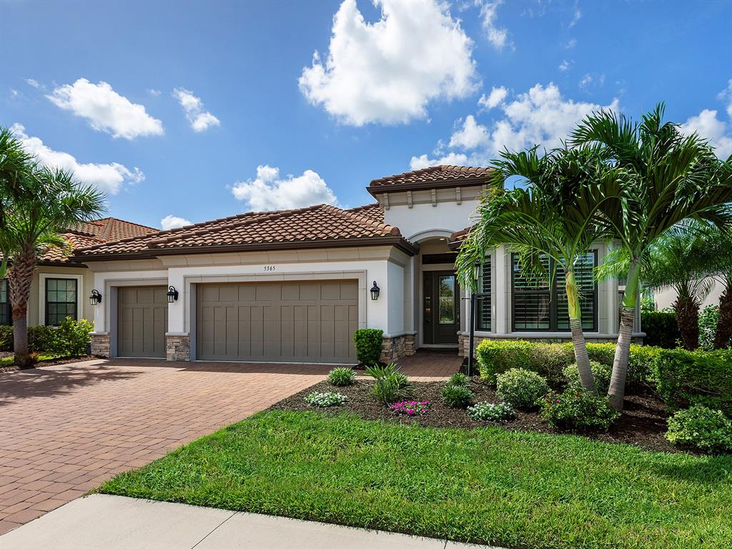 A single-story house with a tile roof, tan stucco walls, and a paved driveway — 5365 SALCANO STREET, SARASOTA, FL