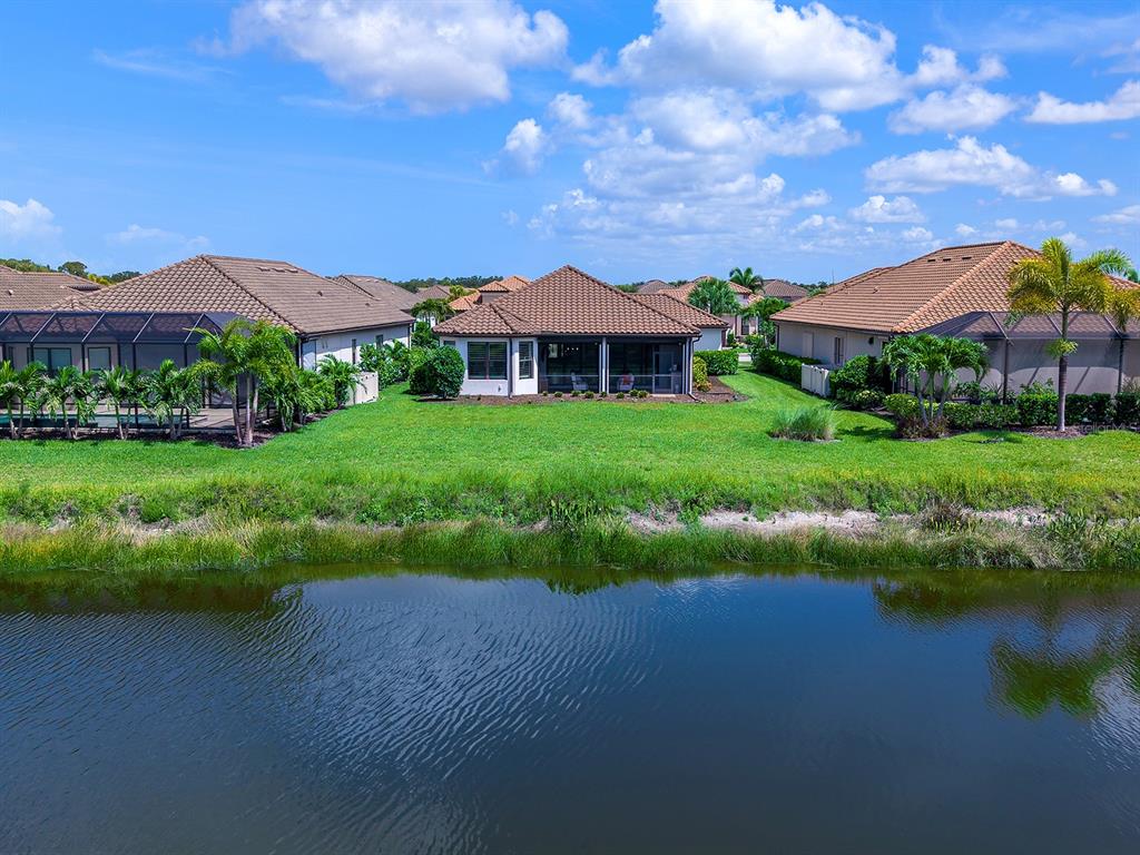 A view of the back of several suburban houses with screened lanais overlooking a pond — 5365 SALCANO STREET, SARASOTA, FL