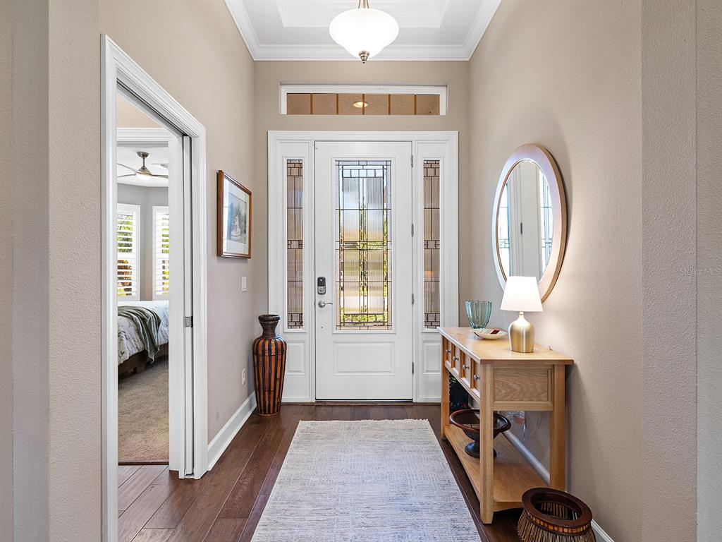 An entryway features a white front door with glass panels, a wood console table, and flooring — 5365 SALCANO STREET, SARASOTA, FL