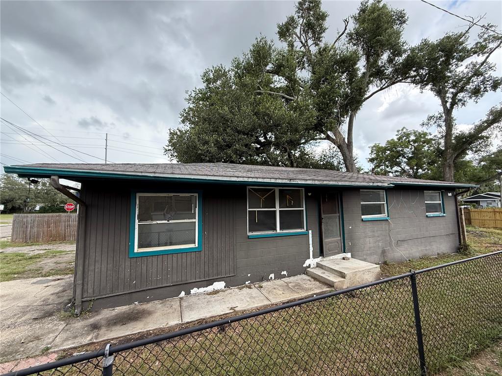 A single-story house with dark gray siding, teal trim, and a chain-link fence — 3307 E NORTH BAY STREET, TAMPA, FL