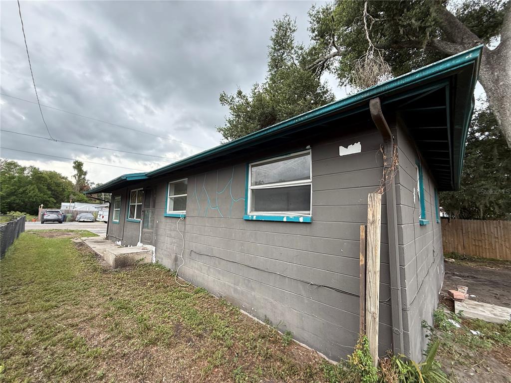 The exterior of a gray, single-story house with teal trim and visible wall cracks — 3307 E NORTH BAY STREET, TAMPA, FL