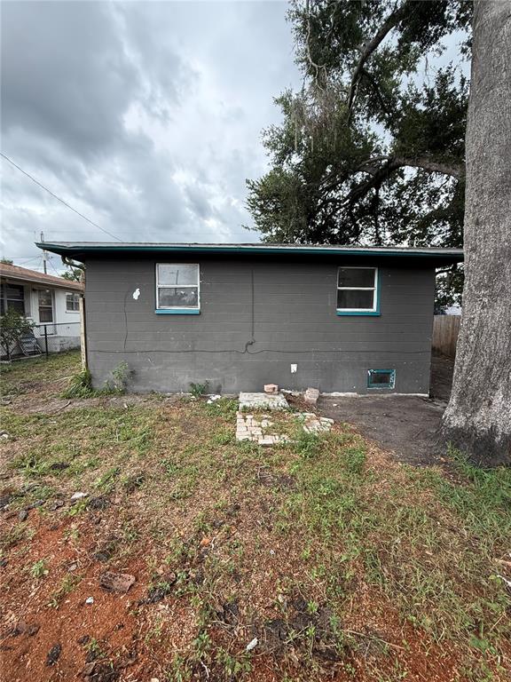The exterior of a gray, single-story concrete block house with two windows and a tree — 3307 E NORTH BAY STREET, TAMPA, FL