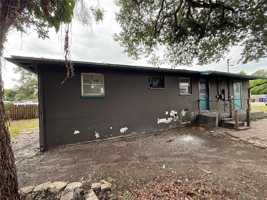 The exterior of a dark-painted house features peeling paint, two doors, and several windows — 3307 E NORTH BAY STREET, TAMPA, FL