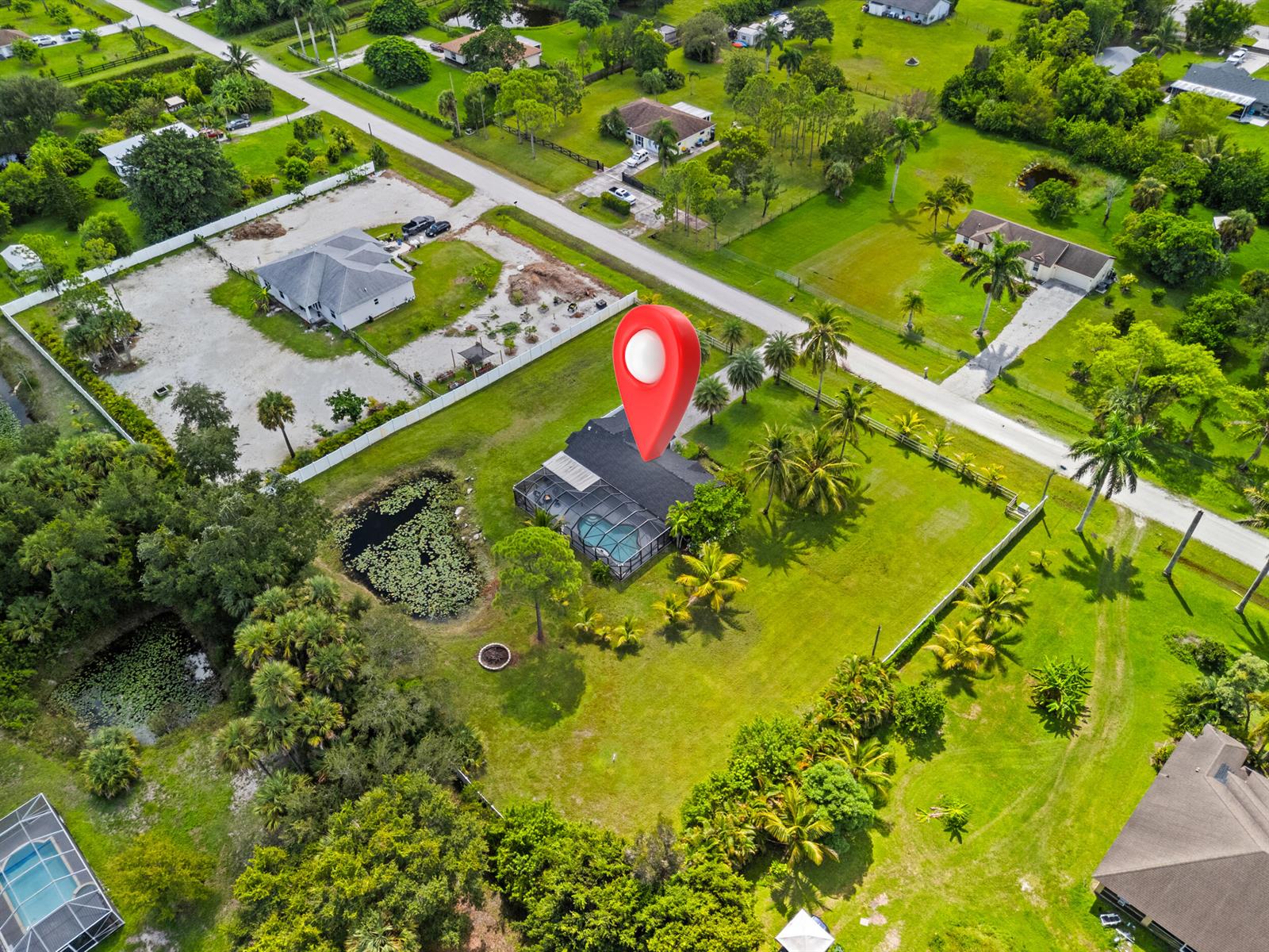 An aerial view shows a house with a screened pool and pond on a large lot — 16857 90th Street N, FL 33470, FL
