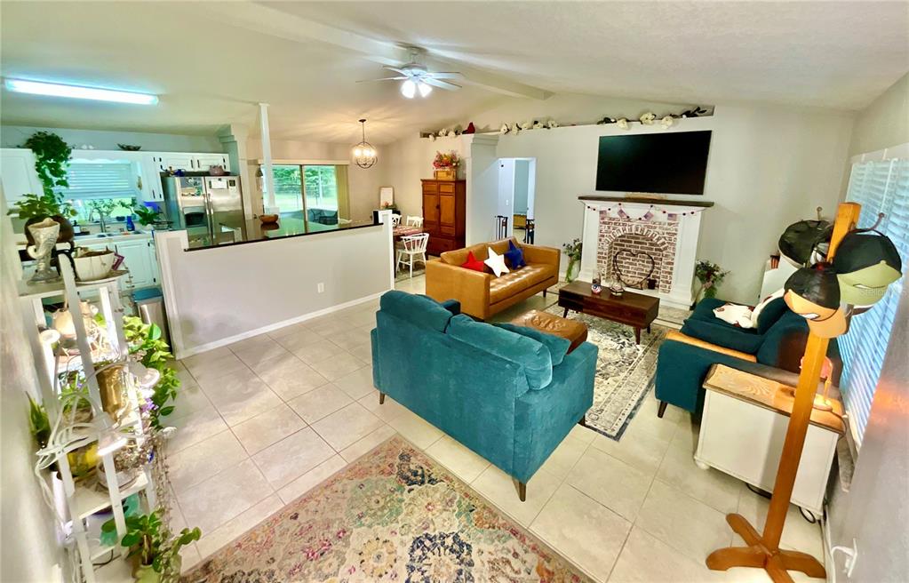 An open-concept living room features tile floors, a brick fireplace, and a kitchen pass-through — 20517 NE 114TH AVENUE, WALDO, FL