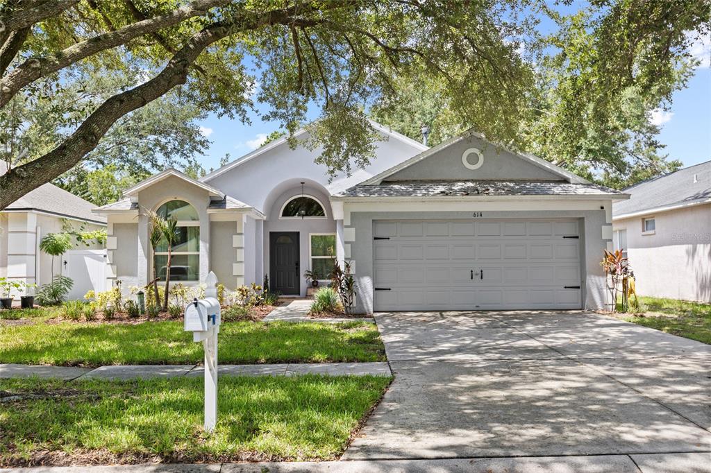 A single-story house with a gray exterior, a two-car garage, and a front yard — 614 SOMERSTONE DRIVE, VALRICO, FL