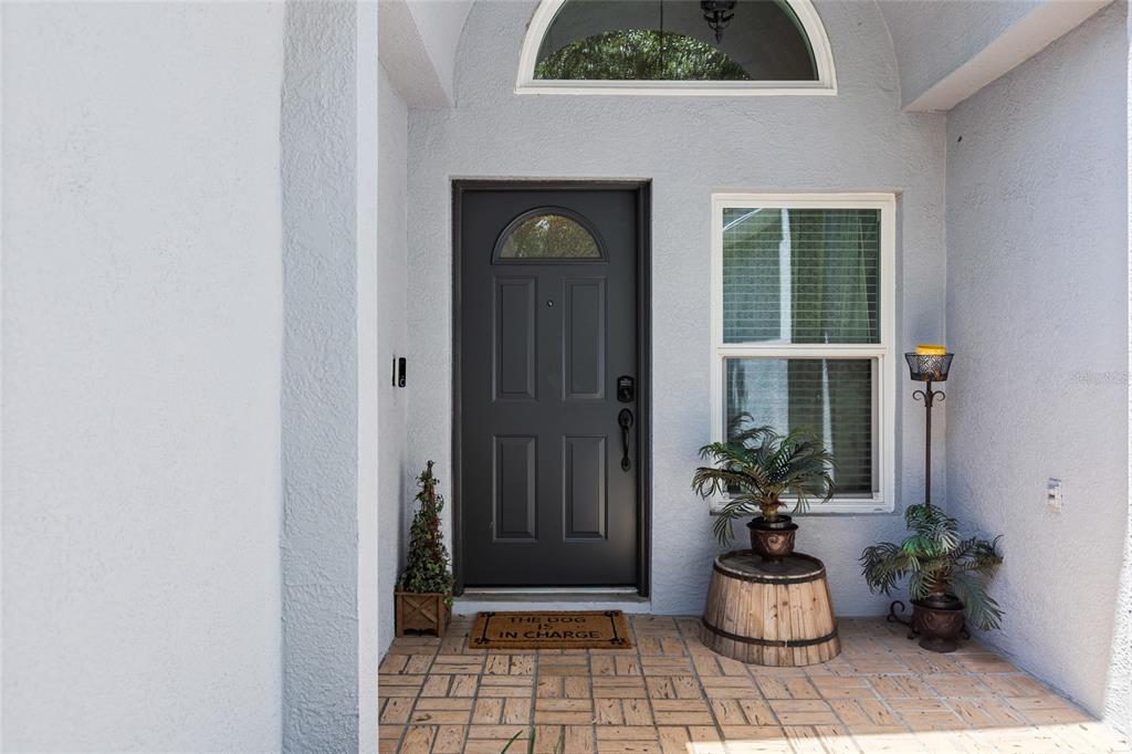 A front entryway features a dark gray door, a tiled porch, and a decorative barrel — 614 SOMERSTONE DRIVE, VALRICO, FL