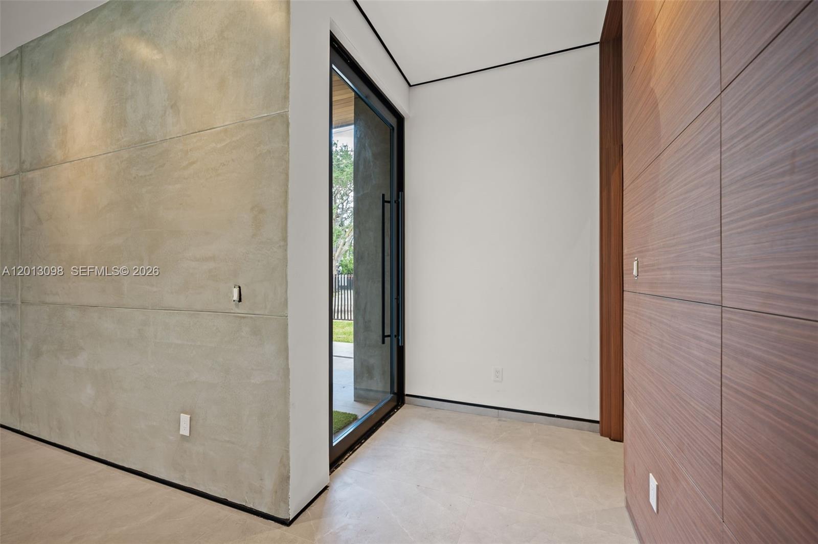 An entryway features a concrete wall, wood paneling, a glass door, and tile flooring — 7740 SW 52nd Ave, Miami FL 33143, MIAMI, FL