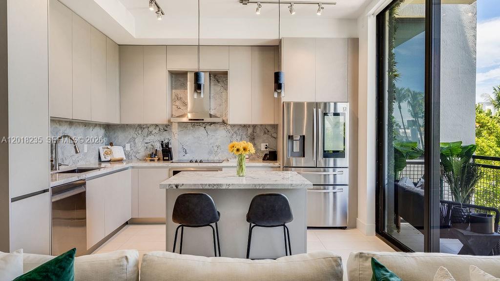 A modern kitchen features light gray cabinetry, marble countertops, and a central island with seating — 1030 15th St # 201, Miami Beach FL 33139, MIAMI BEACH, FL