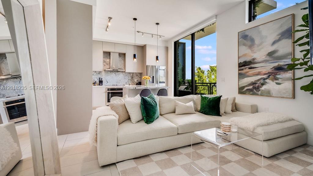 A modern living room features a white sectional sofa, a glass coffee table, and an open kitchen — 1030 15th St # 201, Miami Beach FL 33139, MIAMI BEACH, FL