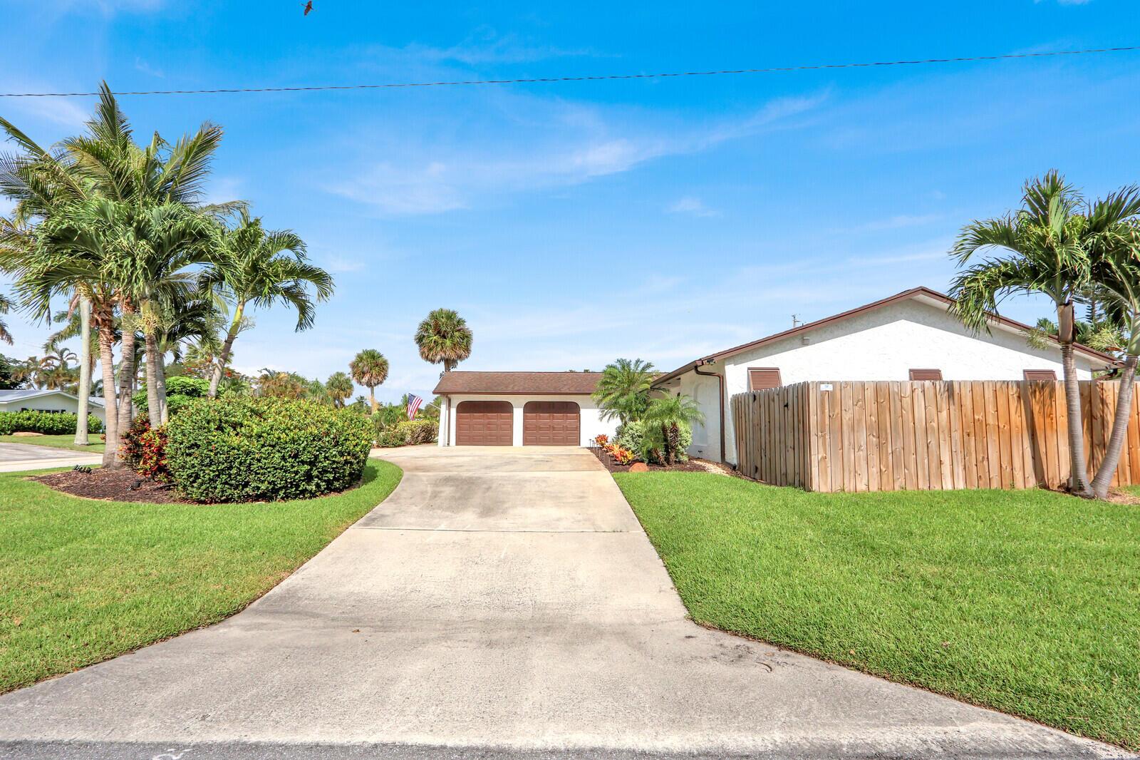 A concrete driveway leads to a two-car garage beside a house with a wooden fence — 3739 Lighthouse Drive, Palm Beach Gardens FL 33410, PALM BEACH GARDENS, FL