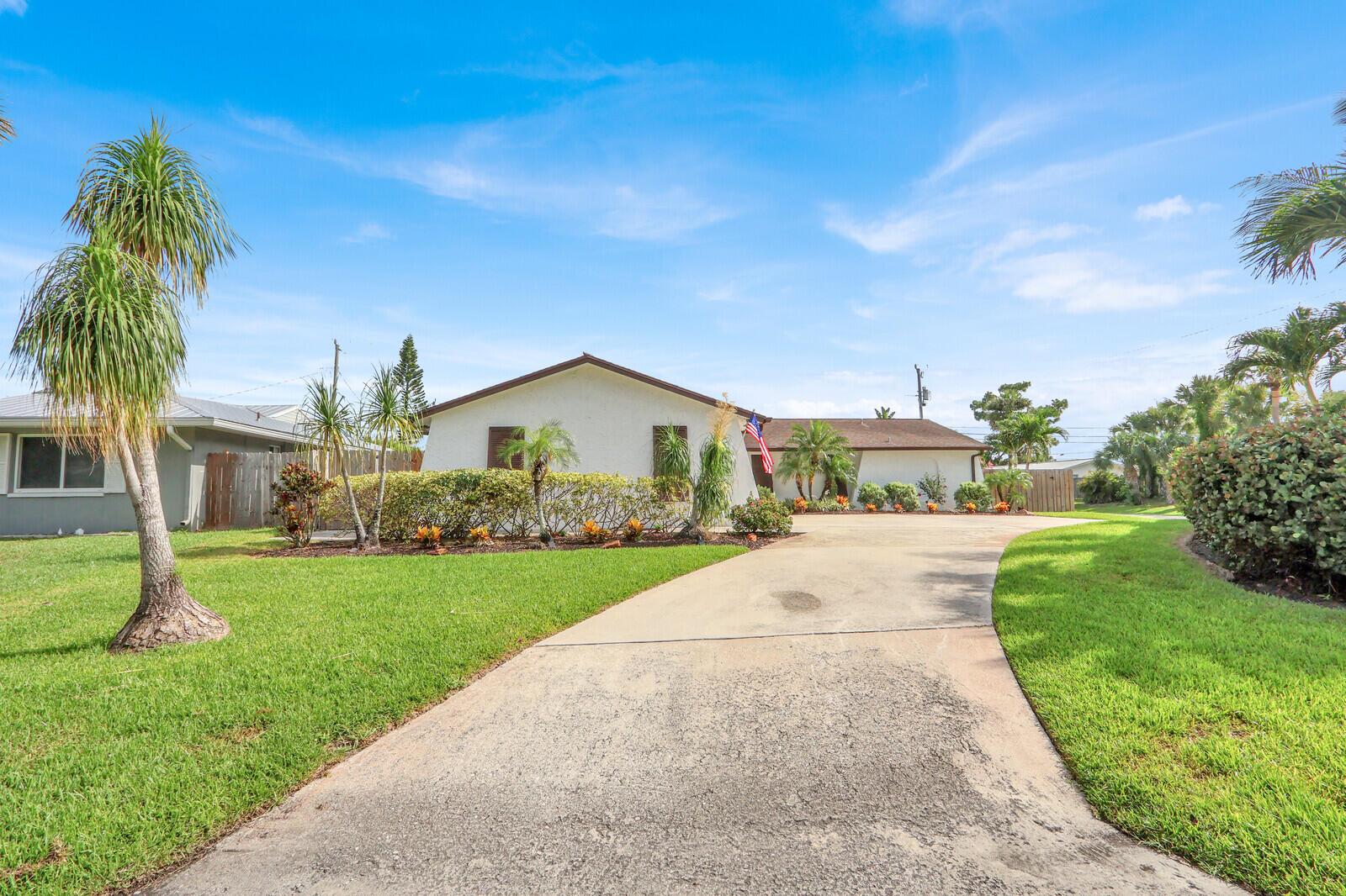 A single-story house with a concrete driveway, palm trees, and a green lawn — 3739 Lighthouse Drive, Palm Beach Gardens FL 33410, PALM BEACH GARDENS, FL