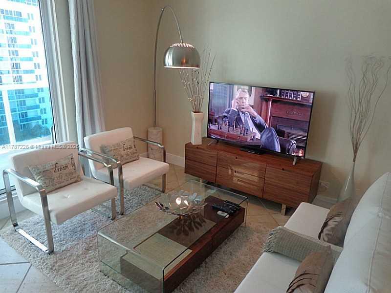 A living room features two white armchairs, a glass coffee table, and a television console — 2301 COLLINS AV, Miami Beach FL 33139, MIAMI BEACH, FL
