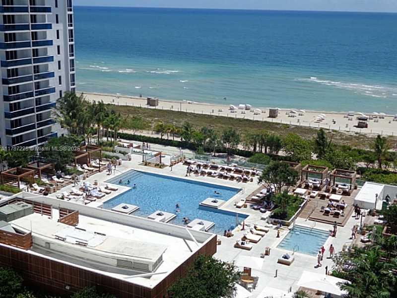 An elevated view of a resort swimming pool area with lounge chairs next to the ocean — 2301 COLLINS AV, Miami Beach FL 33139, MIAMI BEACH, FL