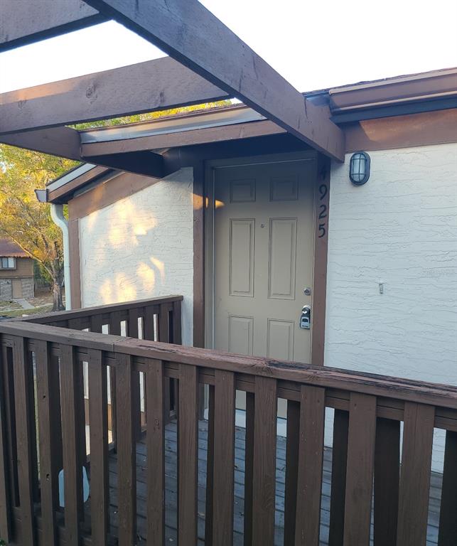 An exterior view of a tan door on a wooden deck with a pergola — 4925 SANOMA VLG UNIT C, ORLANDO, FL