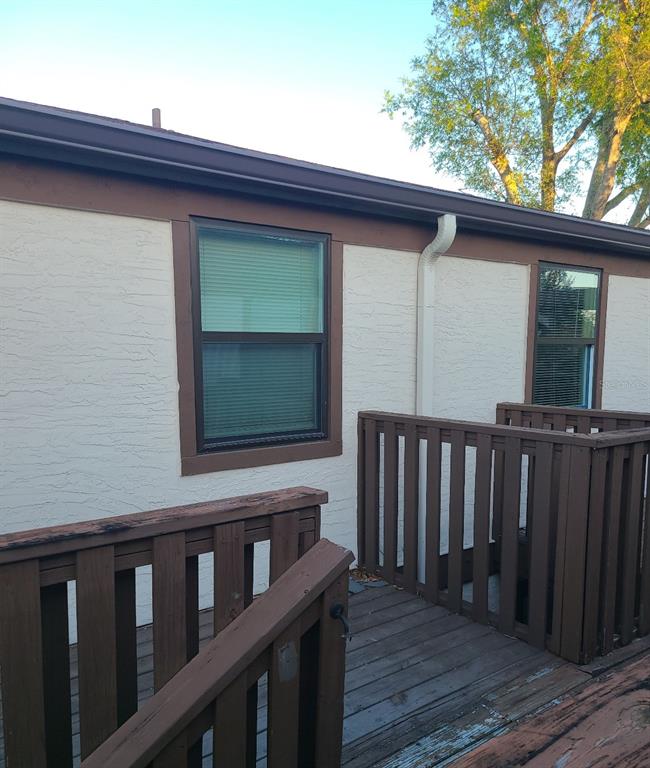 An exterior view of a building with stucco walls, brown trim, and a wooden deck — 4925 SANOMA VLG UNIT C, ORLANDO, FL
