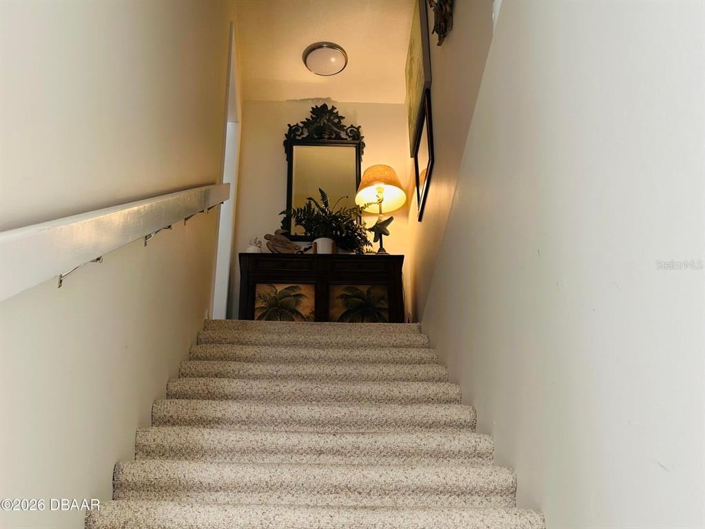 A carpeted staircase leads to a landing featuring a console table, mirror, and lamp — 4758 S ATLANTIC AVENUE UNIT 6, PONCE INLET, FL