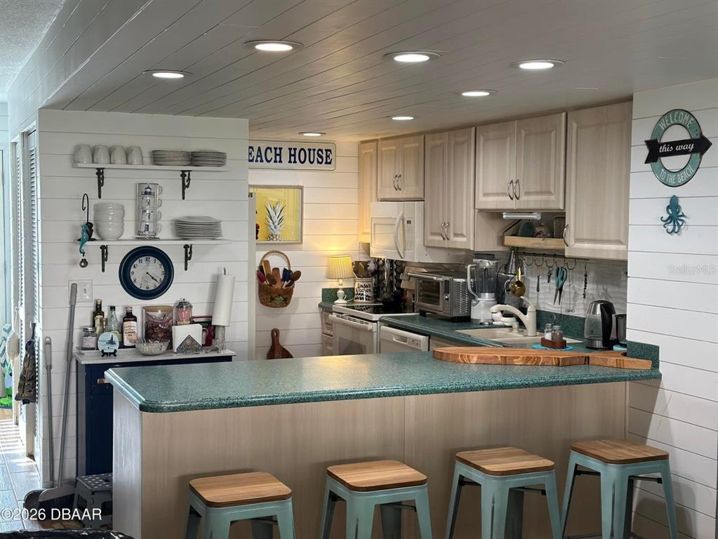 A kitchen features a green countertop island with four stools and white shiplap walls — 4758 S ATLANTIC AVENUE UNIT 6, PONCE INLET, FL