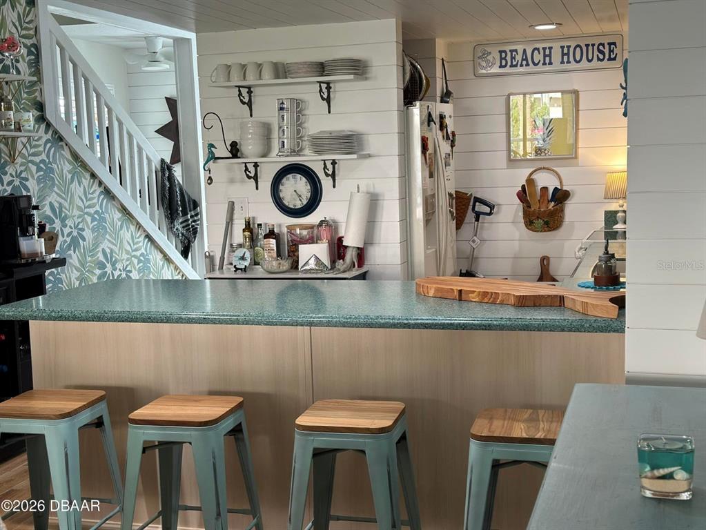 A kitchen island with four stools sits in front of a white shiplap wall — 4758 S ATLANTIC AVENUE UNIT 6, PONCE INLET, FL