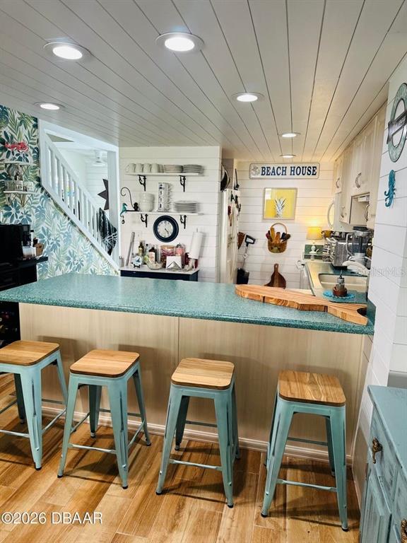 A kitchen features a teal countertop island with four stools and white shiplap walls — 4758 S ATLANTIC AVENUE UNIT 6, PONCE INLET, FL