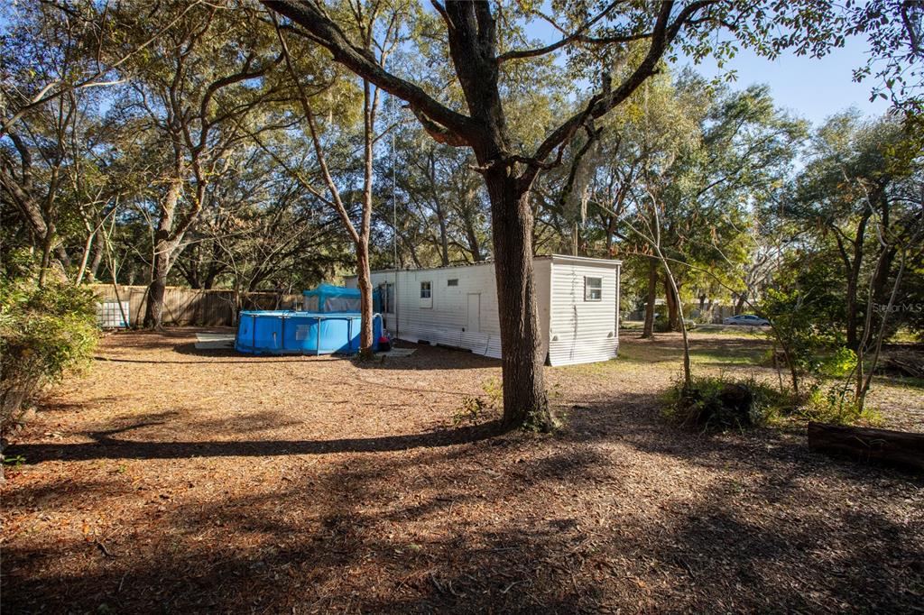 A white mobile home sits in a wooded yard with a blue above-ground swimming pool — 270 BAY STREET, HAWTHORNE, FL