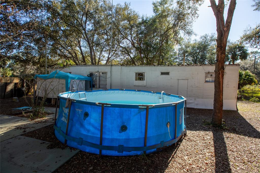 A blue above-ground swimming pool sits in the yard next to a white mobile home — 270 BAY STREET, HAWTHORNE, FL