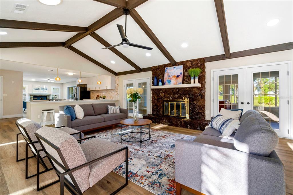 A living room features a vaulted ceiling with exposed beams, a stone fireplace, and furniture — 5391 NW 76TH COURT, OCALA, FL