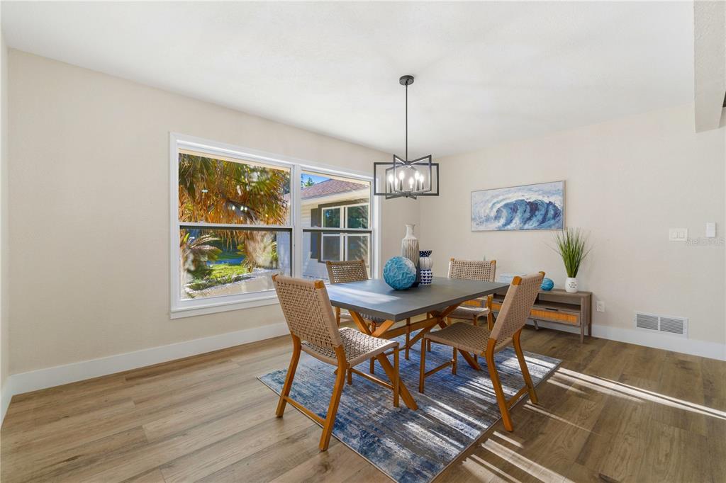 A dining room features a square table, woven chairs, a blue rug, and a chandelier — 5391 NW 76TH COURT, OCALA, FL