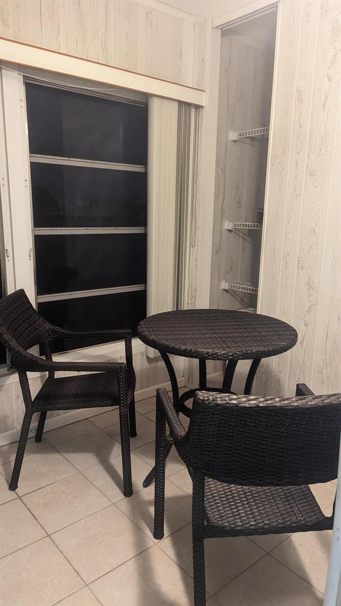 A small dining area with a round wicker table, two chairs, and a built-in pantry — 2053 Cornwall C, Boca Raton FL 33434, BOCA RATON, FL